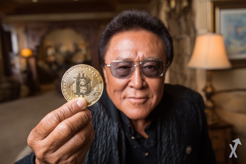 L'investisseur réputé Robert Kiyosaki avec des lunettes, tenant une pièce de bitcoin