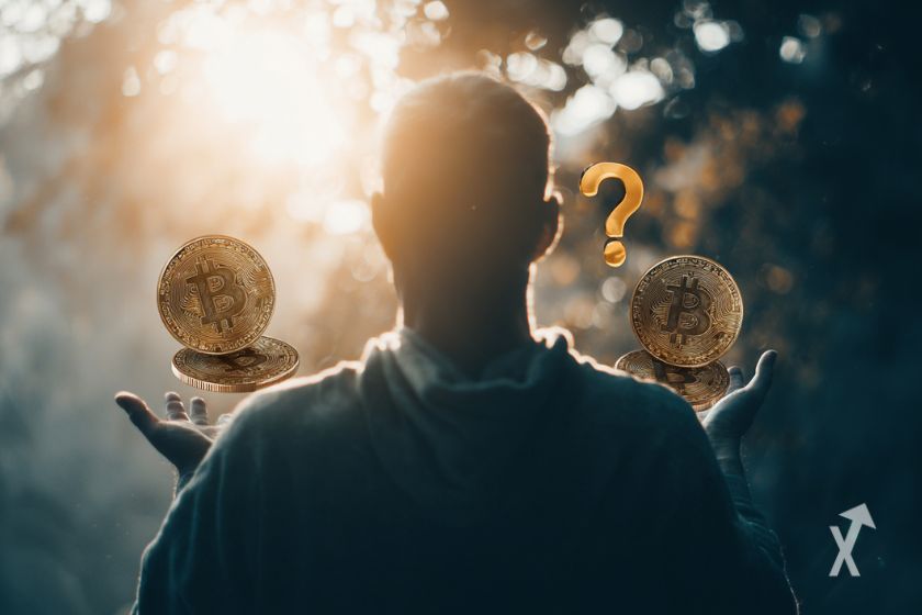 Un homme vu de dos, face au soleil, tenant des pièces de Bitcoin dans ses mains