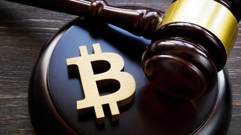 Une gavel et un logo bitcoin sur du bois, pour réguler la cryptomonnaie